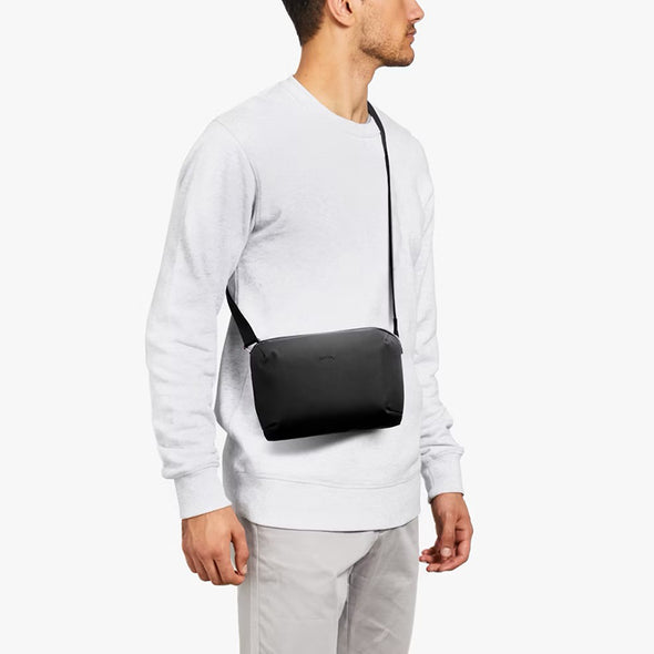 Person wearing a black crossbody bag on a white background