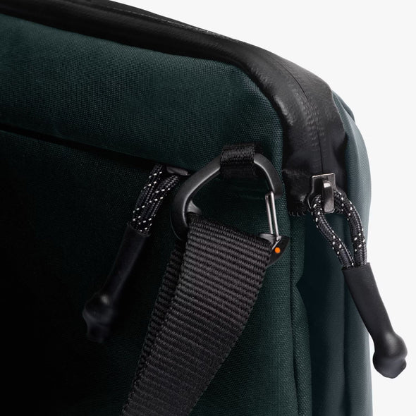 Close-up of a Venture Travel Crossbody by Bellroy Deep Ocean with black straps and zippers on a white background
