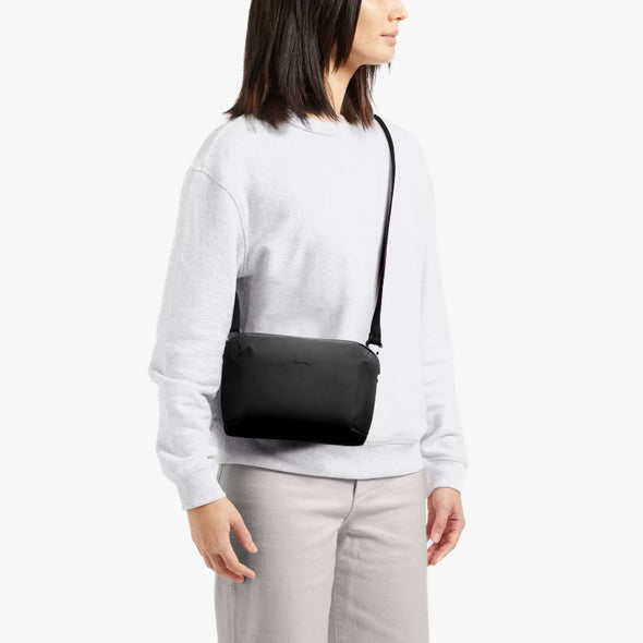 Person wearing a black crossbody bag on a white background
