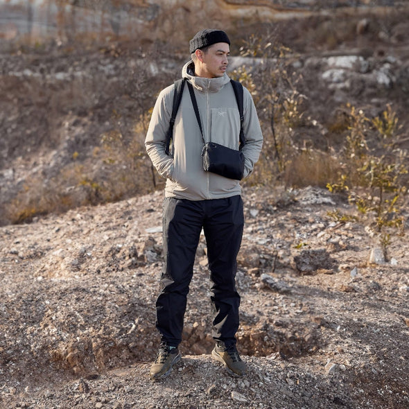 Man standing in a rocky, barren landscape wearing outdoor gear.